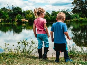 A boy and a girl next to a water pond